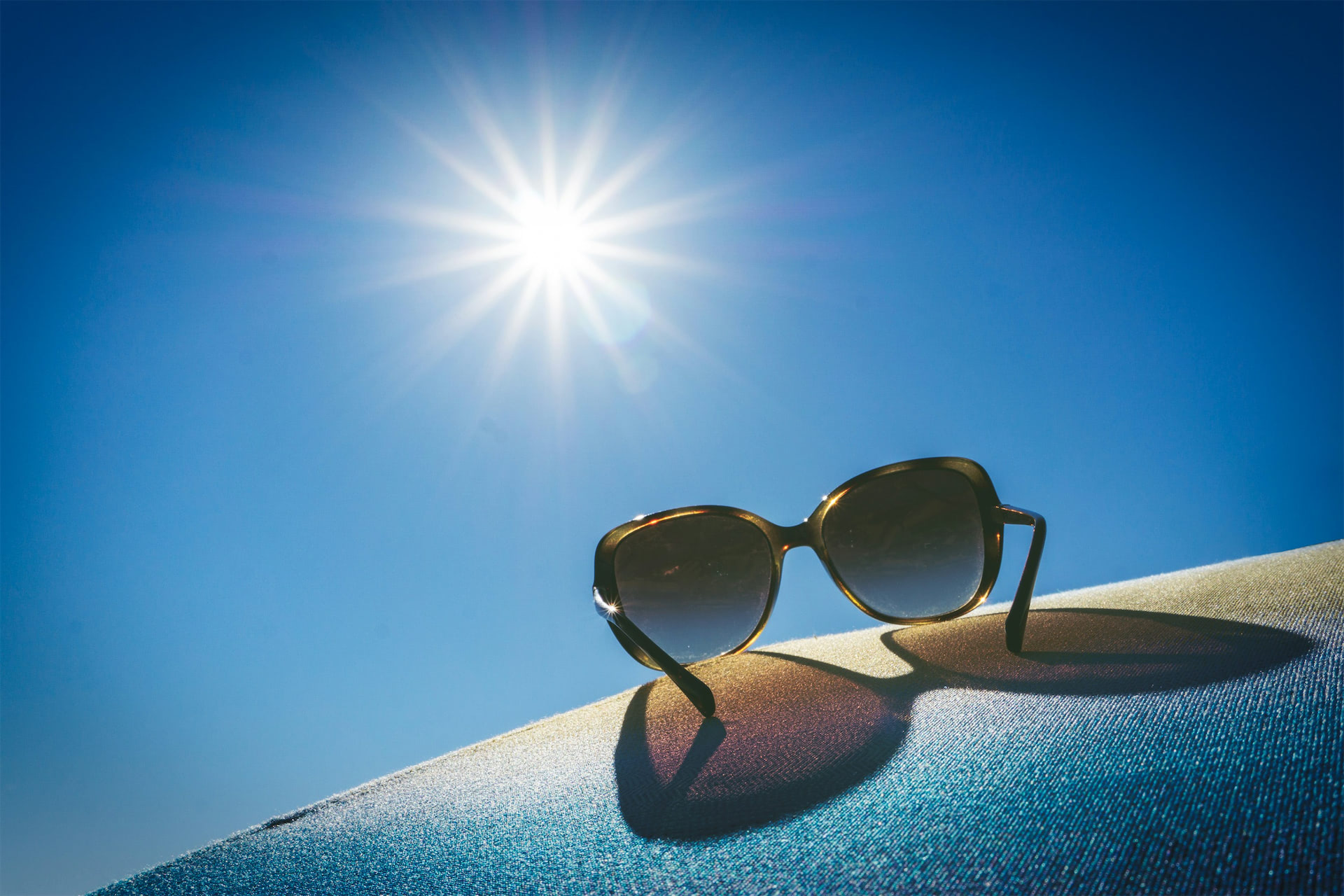 Sunglasses and sunshine imagery supporting the tanning lifestyle theme